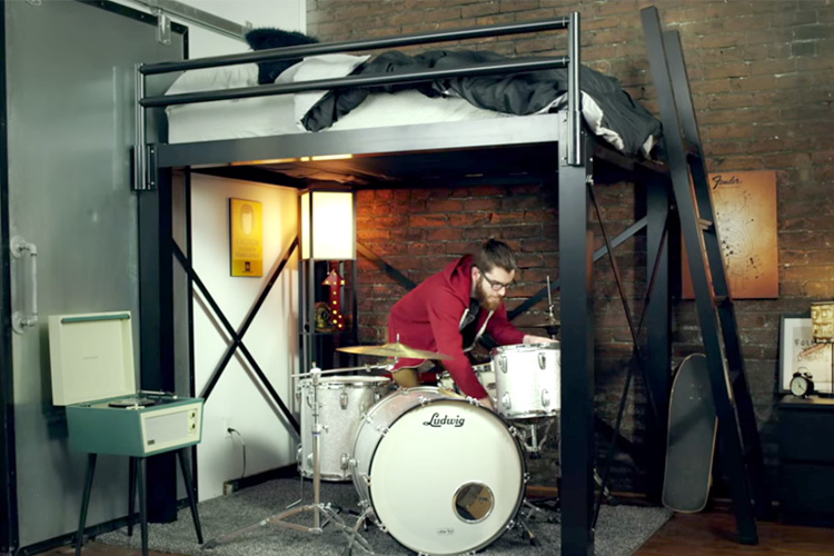 A Francis Loft's & Bunks Loft Bed with a man setting up his drum set underneath now that he has additional space.