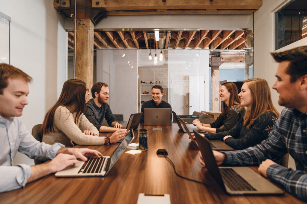 A large team meeting with people on their laptops.