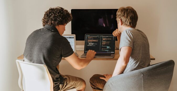 two guys coding on a laptop