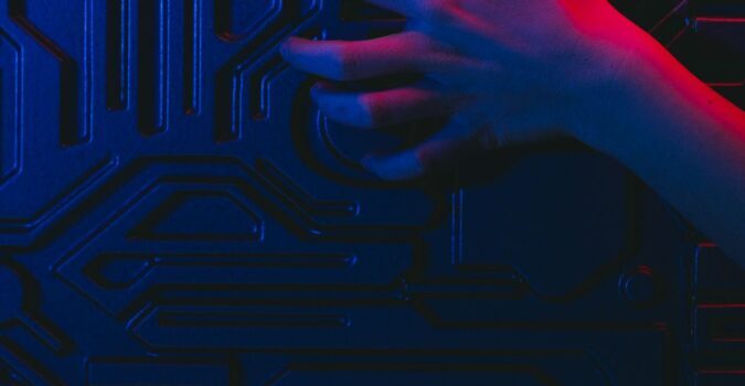 Close-up of a human hand touching a circuit board with neon lighting